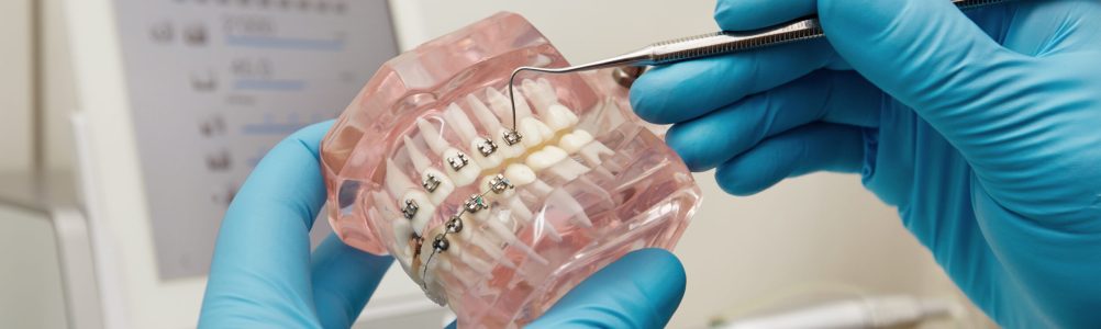 Prosthetics hands while working on the denture, false teeth, a study and a table with dental tools. Dental laboratory. Prosthetics hands while working on the denture, false teeth, a study and a table with dental tools. Dental laboratory.